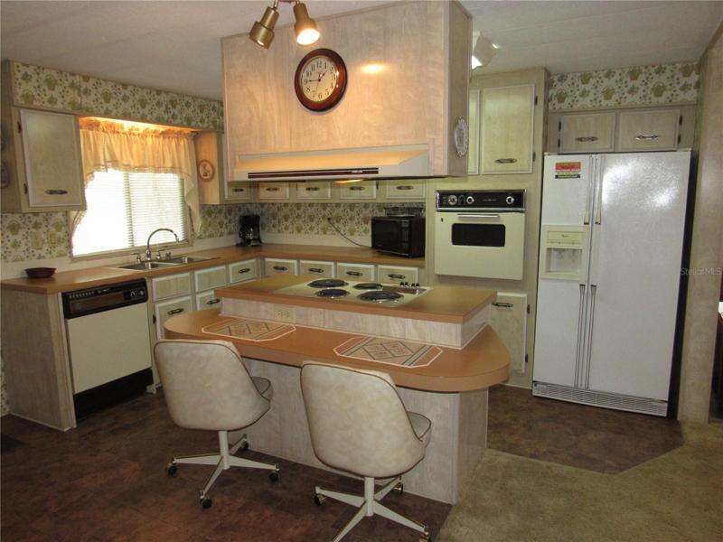 Island with breakfast bar and cooktop with vent hood.