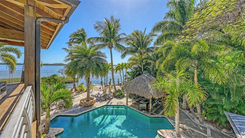 Main house terrace overlooking the pool and tiki-hut lounging areas.