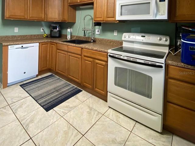 Kitchen is located downstairs and has tile flooring. Lots of cabinet and counter space PLUS  there is room for storage racks AND there is an additional Storage room and walk-in Pantry located under the stairs.  Dishwasher, Microwave and Glass-top range included.