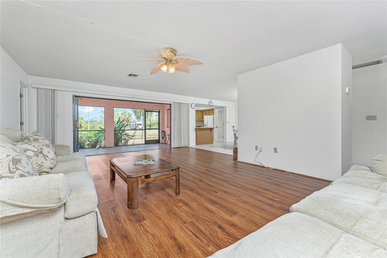 Large Great Room looking to stacking pocket sliders to Lanai with Kitchen beyond.