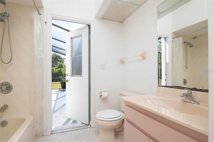Guest bathroom with single vanity, tub/shower combo and access to the pool area.