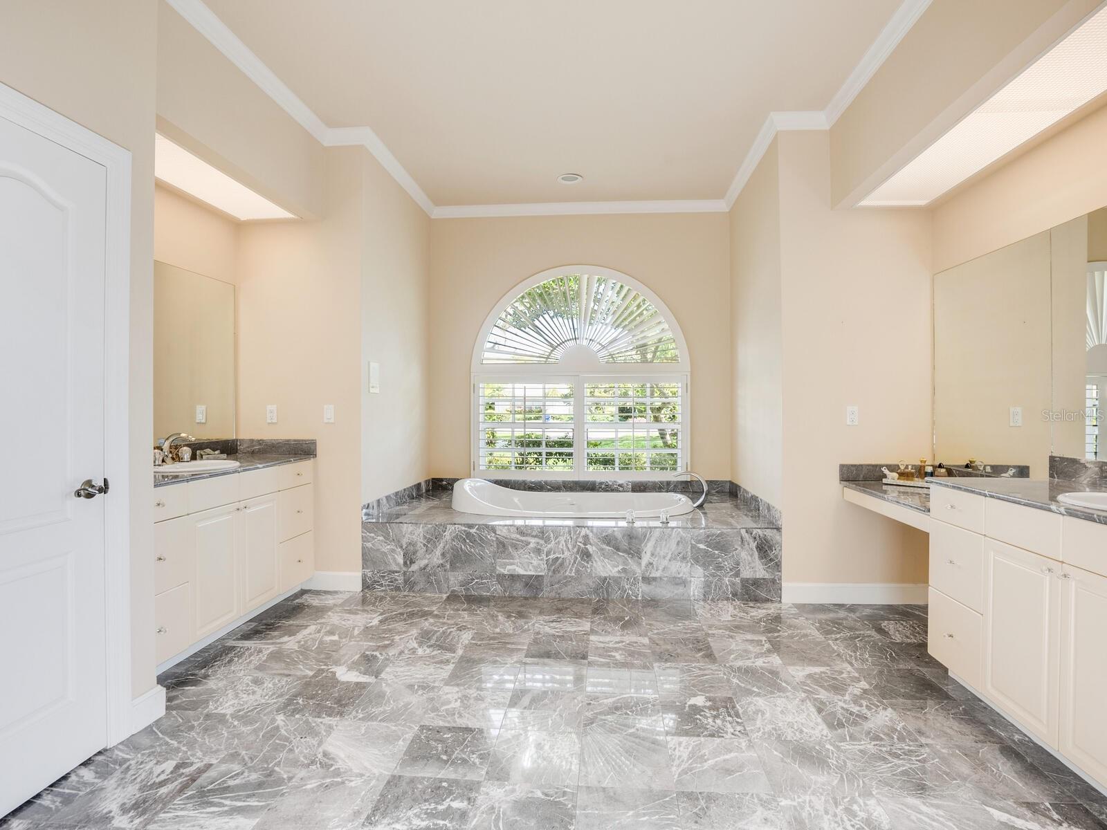 Primary Ensuite Bath with marble flooring, dual sinks and a vanity.