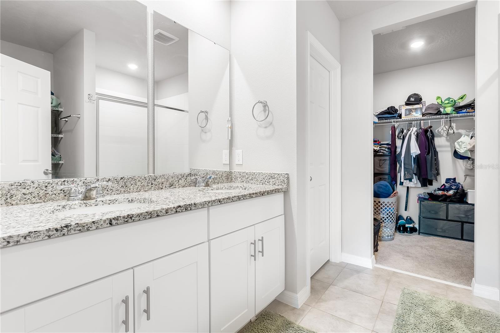 Primary bathroom dual sinks, walk-in closet, and private toilet room