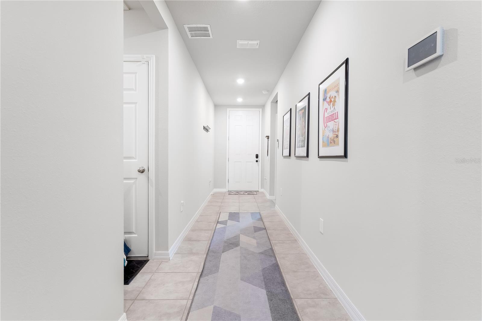 Hallway with front door. Left alcove leads to the garage entrance, 3rd guest bedroom, and laundry room. Closer to the front door on the right leads to guest bedrooms 1 and 2 as well as the guest bathroom.