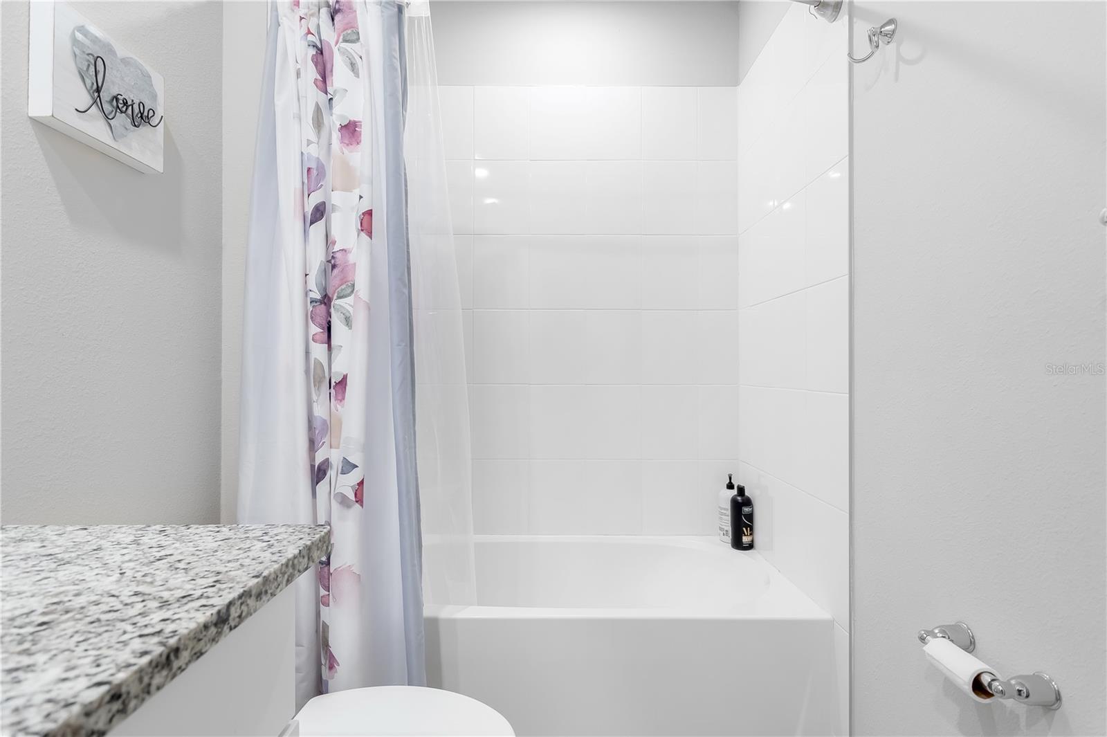 Guest bathroom with shower curtain open.