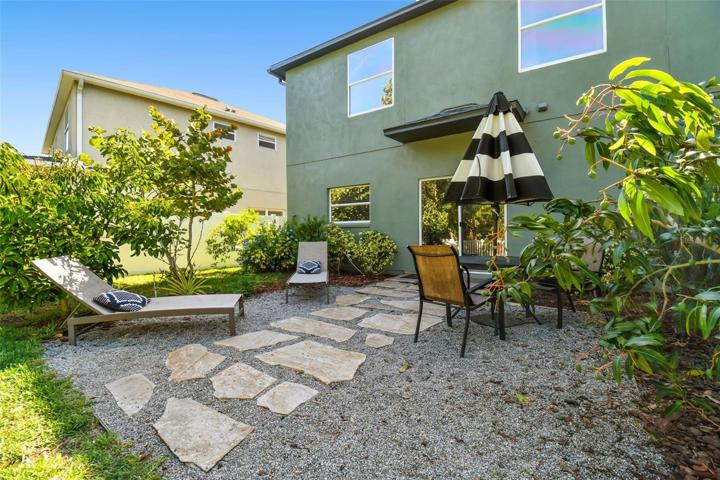 Relaxing back patio area surrounded by lush landscaping.