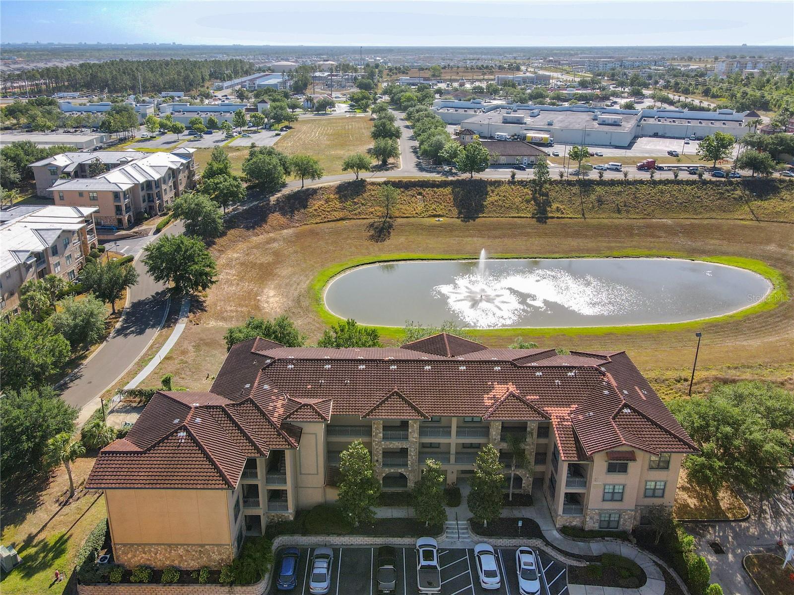 Overhead view of front of condo building with pond behind