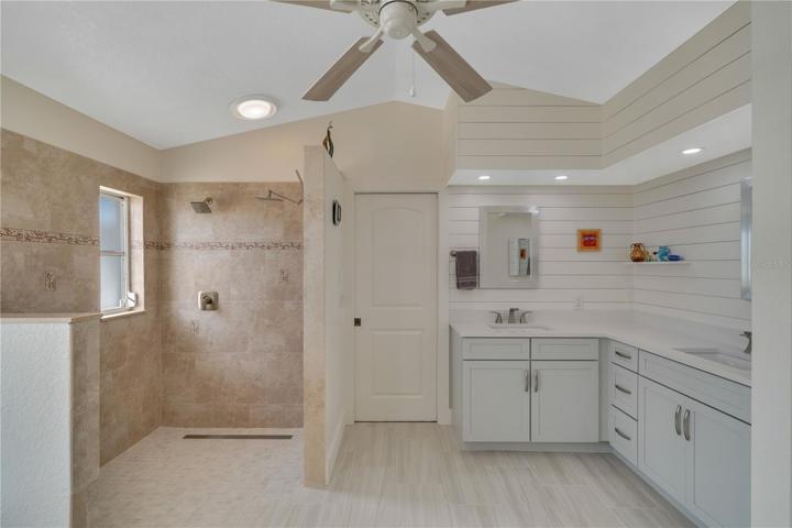 Large custom tiled walk in shower, custom Kraft Maid vanity cabinets and quartz counter top with two sinks
