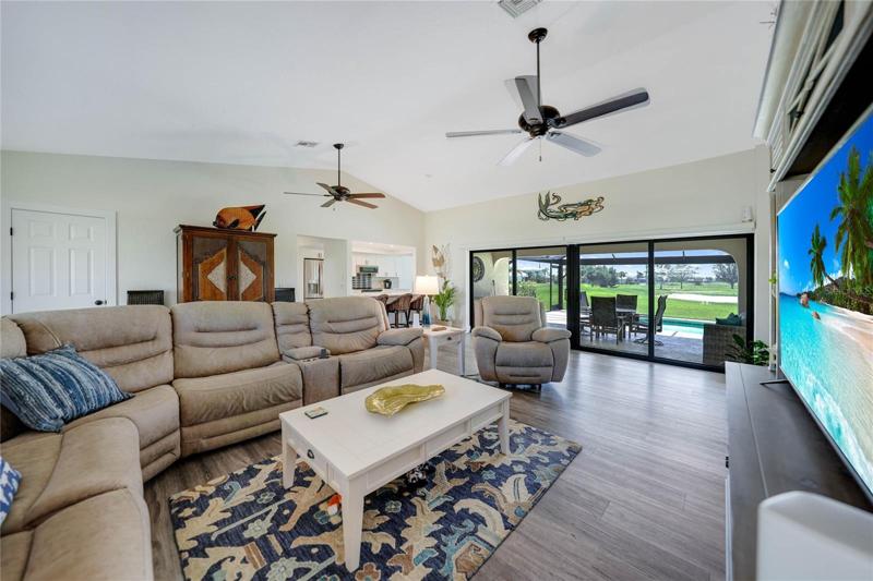 great room design with a walk in entry closet, breakfast bar, two ceiling fans, vaulted ceilings and hurricane impact shutters with electric blinds.  Luxury vinyl plank flooring is easy to maintain