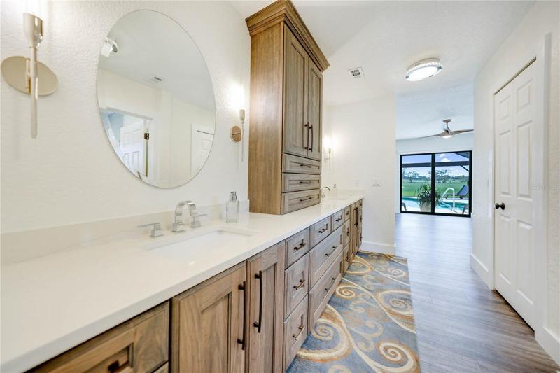 master bathroom vanity has two sinks separated by a storage cabinet and is located in between the master bedroom and the office.  The cabinetry and finishes are exquisite and provide so much storage.  To the right is a walk in closet and a bathroom with a walk in shower