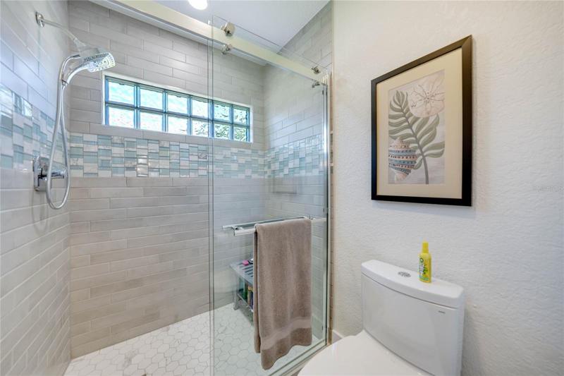 beautiful tile work with a rolling glass door and large glass block window gives this room a light and open feel.  