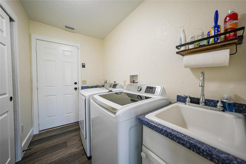 laundry room connects to the garage and has a large sink with storage, additional counter space and a large closet