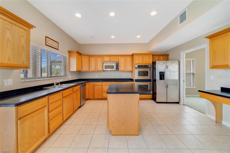 The comfortable kitchen is well equipped with plenty of cabinet and counter space, a closet pantry, island with bar seating and a large window over the sink for a view of the lanai and pool!