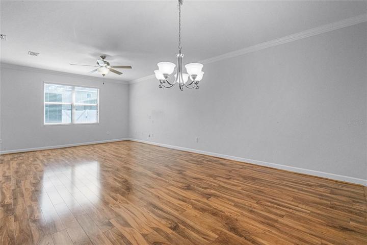Family room and dining room area with freshly painted light walls, crown molding and ceiling fan!