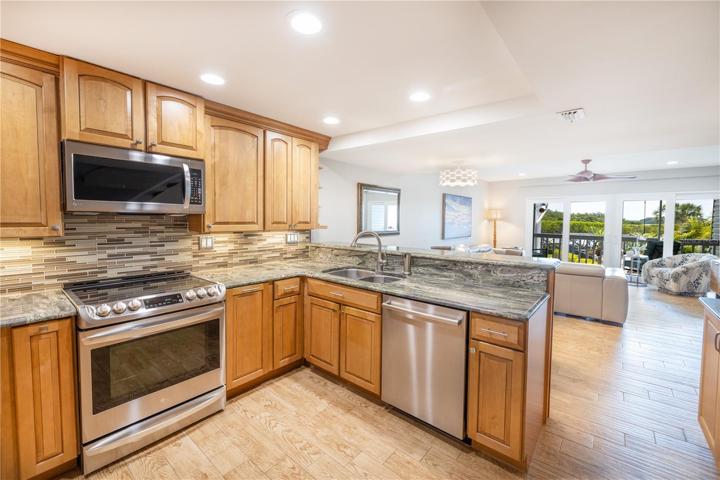 Kitchen with Kraftmaid maple cabinets, under cabinet lighting, granite counters, glass tile back splash and a breakfast bar