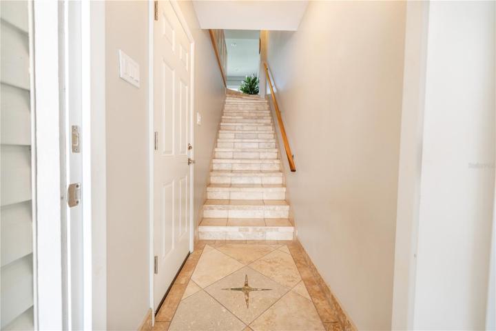Entry with a compass design and travertine stairs to the first level living area