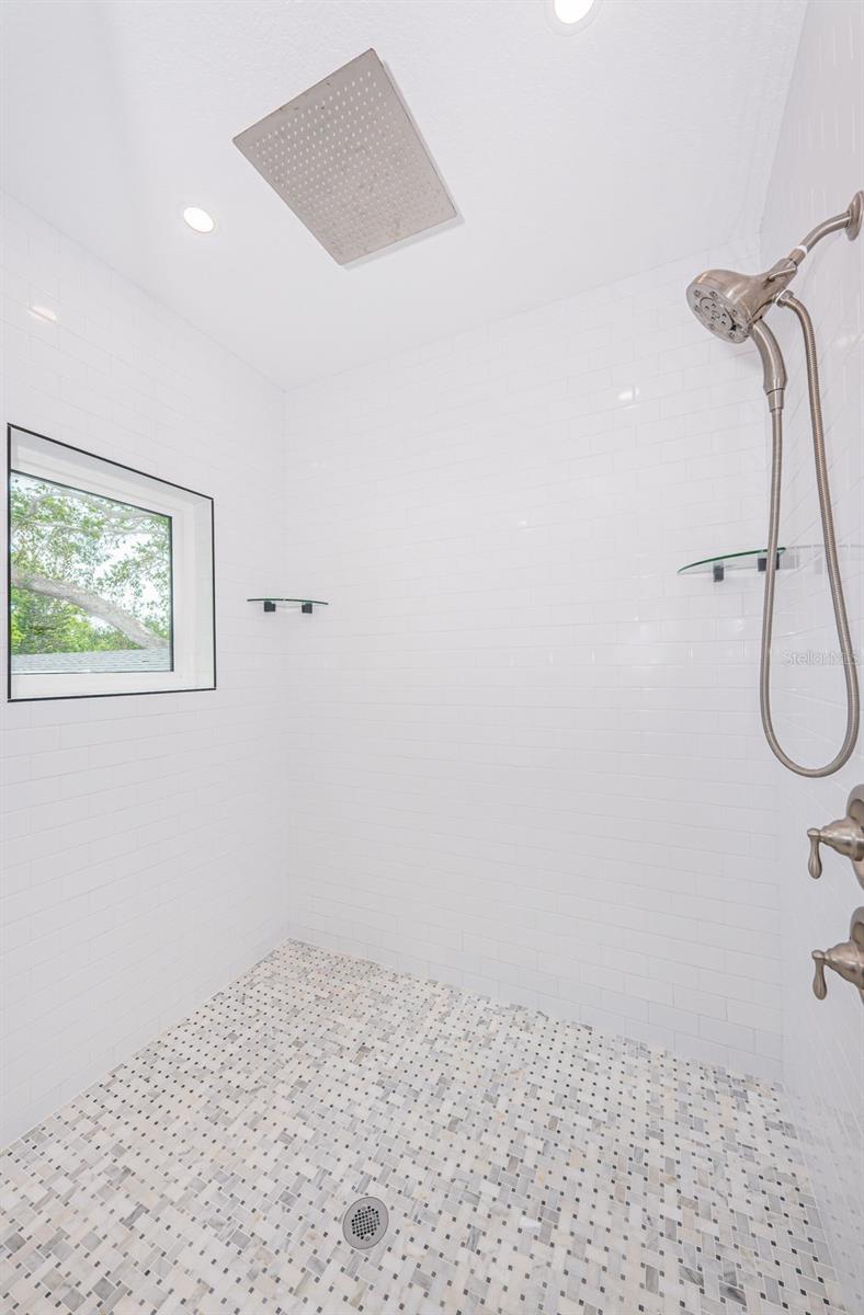 Upstairs oversized shower with frameless glass and dual heads.
