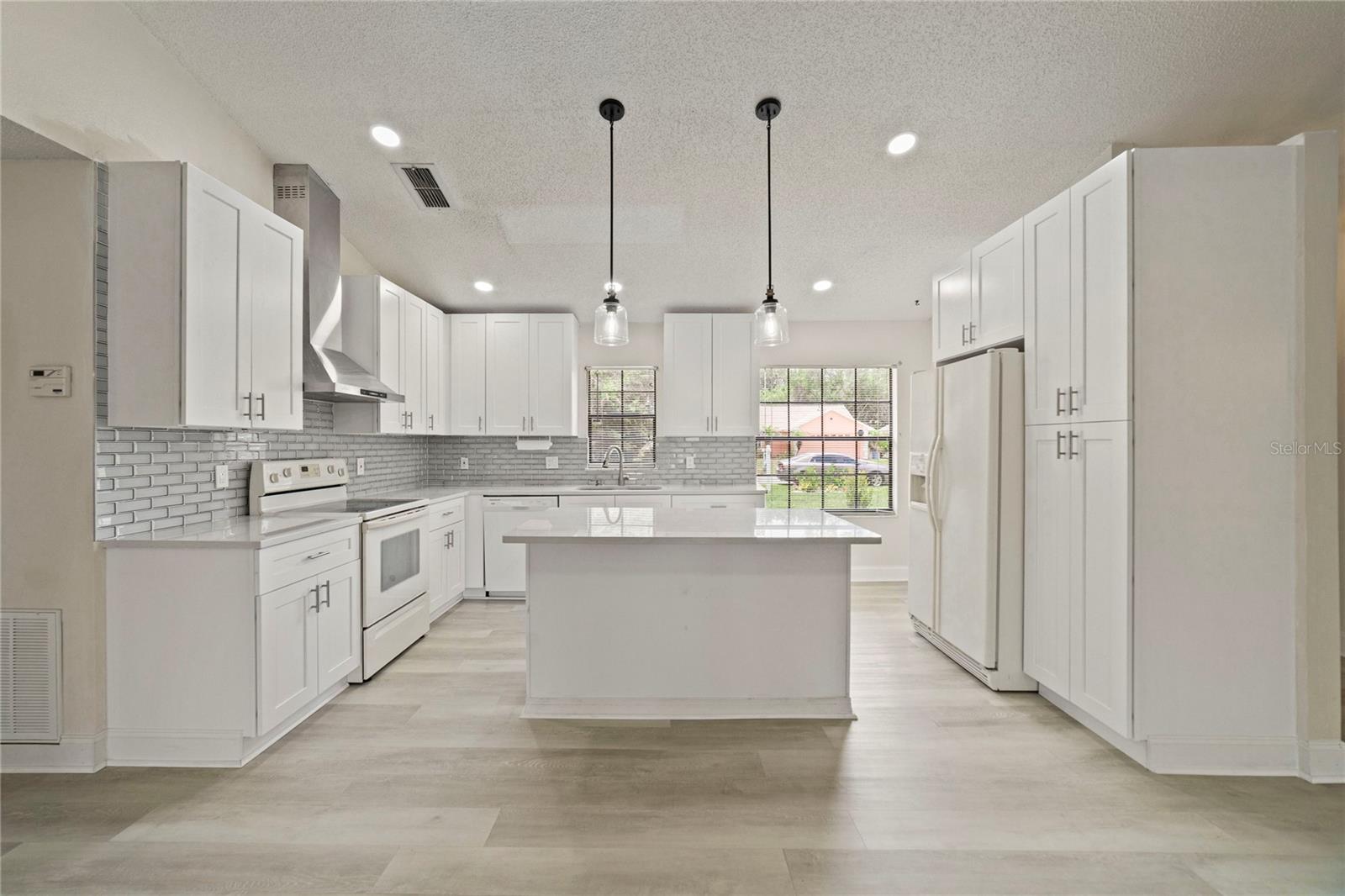 Ideally situated in the heart of this home, the renovated kitchen is a must see with perfectly laid out SHAKER STYLE CABINETRY, stainless steel range hood, glass SUBWAY TILE BACKSPLASH, a large ISLAND with breakfast bar seating and two windows for more great light!