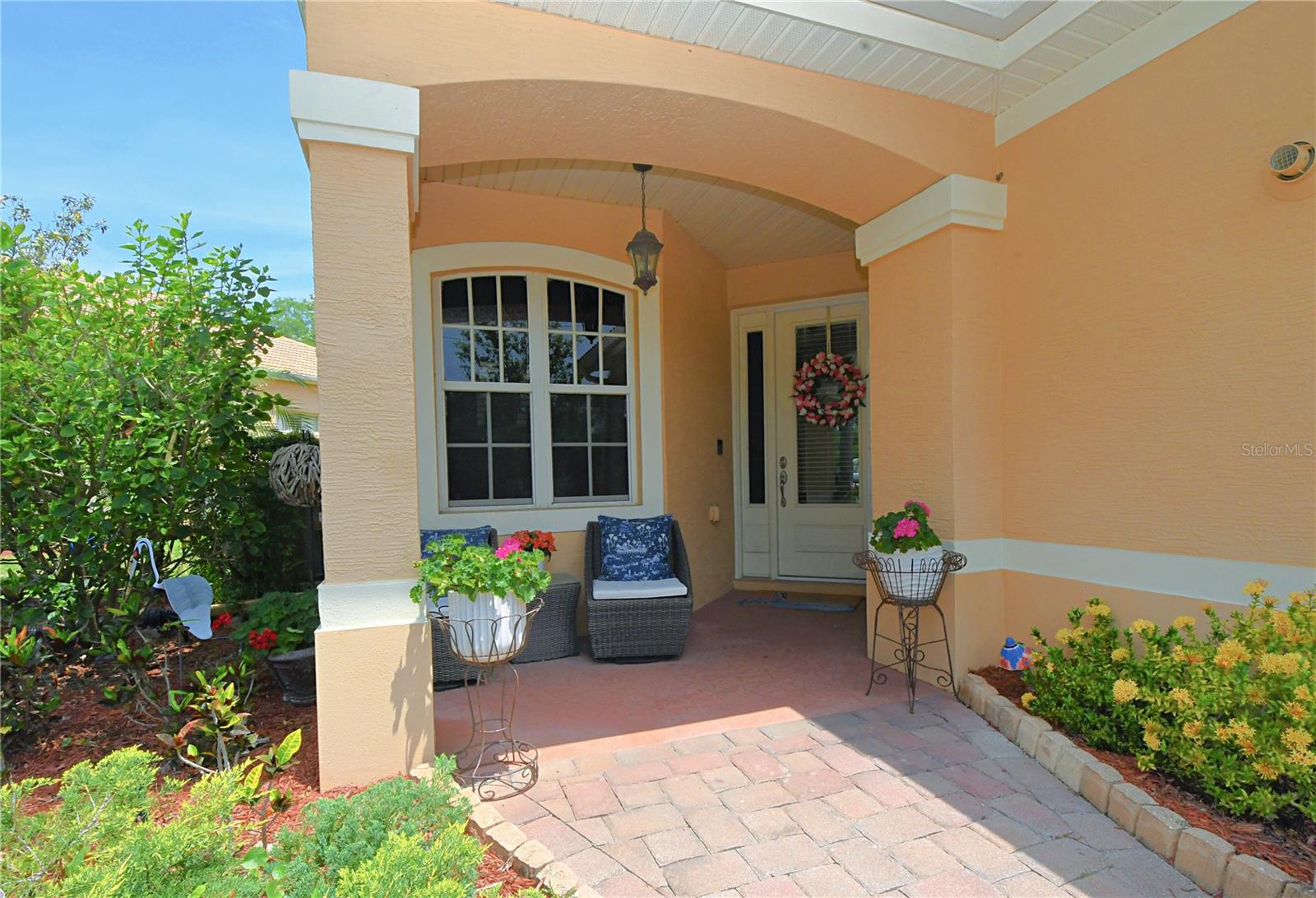 The home greets you with a stone-paved driveway that leads to a covered front porch adorned with a captivating glass-panel front door, with an additional side light and an exterior pendant light that beckons you in.