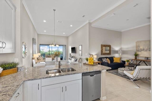 Stunning Kitchen off the front entryway showing the island overlooking the open floorplan featuring 12'+ Ceilings throughout