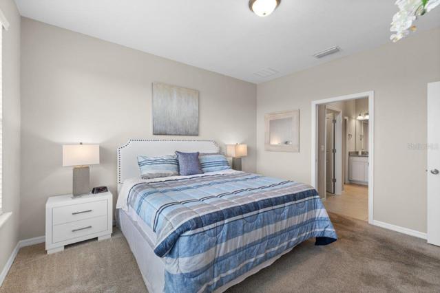 Owners suite off of the living room featuring lake views, en-suite bathroom, and walk-in closets