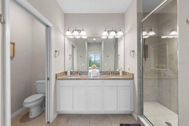 Owners en-suite bathroom featuring dual sinks, water closet, and a walk-in shower