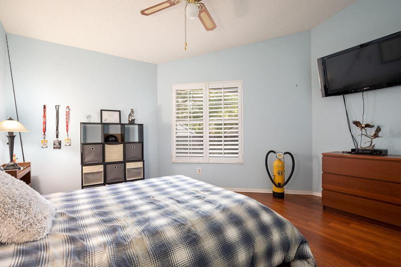 Roomy 2nd bedroom with plantation shutters and wide plank warm wood engineered flooring
