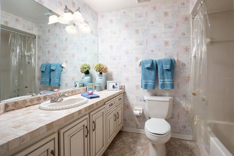 Enchanting second bathroom with tumbled marble flair to the countertops, roomy tub w/ shower and lots of counter space and storage.