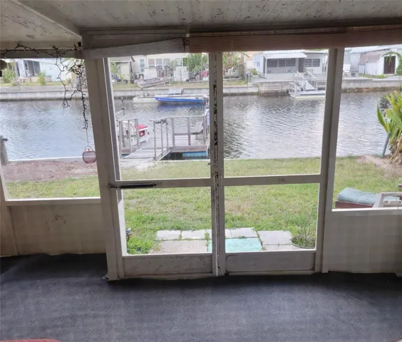This is the other  larger screened porch. It includes a working Hot tub  with a view of the canal!. The entrance to the workshop/shed area is to the right.