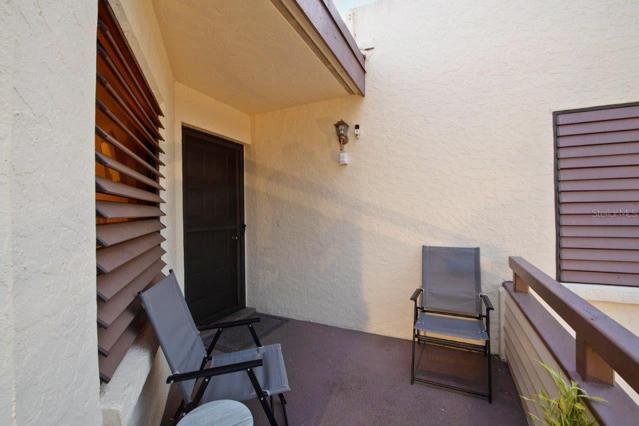Partially covered front porch featuring security camera, hurricane shutters, and screened front door