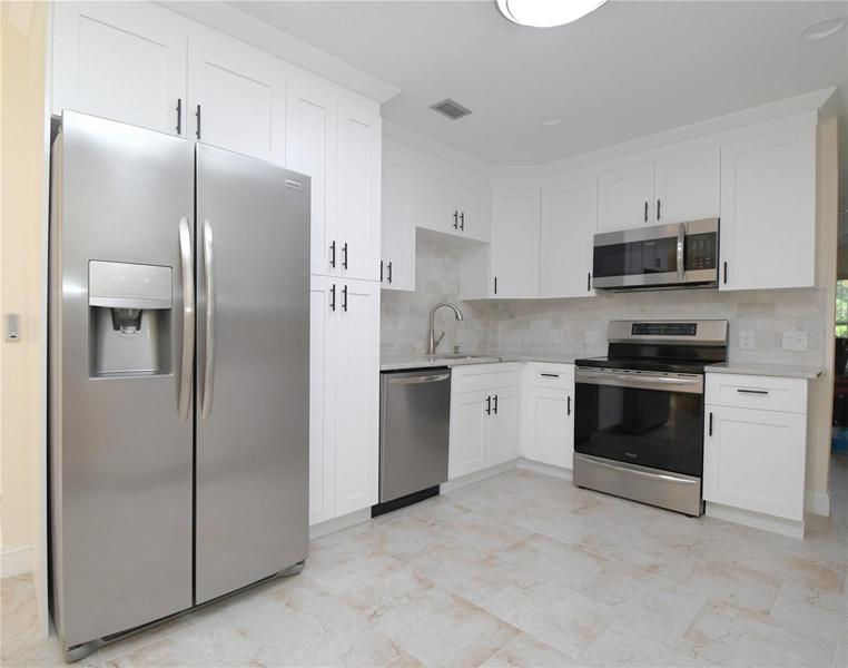 Kitchen featuring matching stainless steel appliances, including an Induction cooktop. Granite countertops. Garbage disposal in the sink. Recessed lighting.