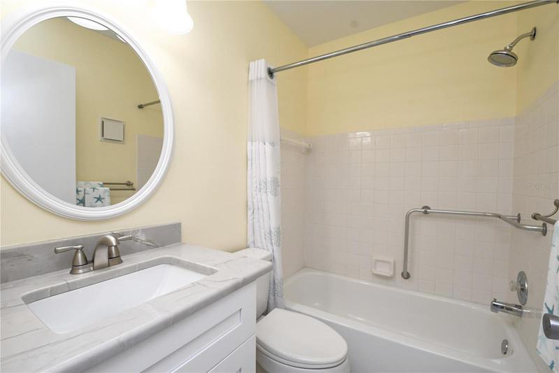 Bathroom #2 - featuring a bathtub with handicapped railing. New vanity with granite countertop and new light fixtures.
