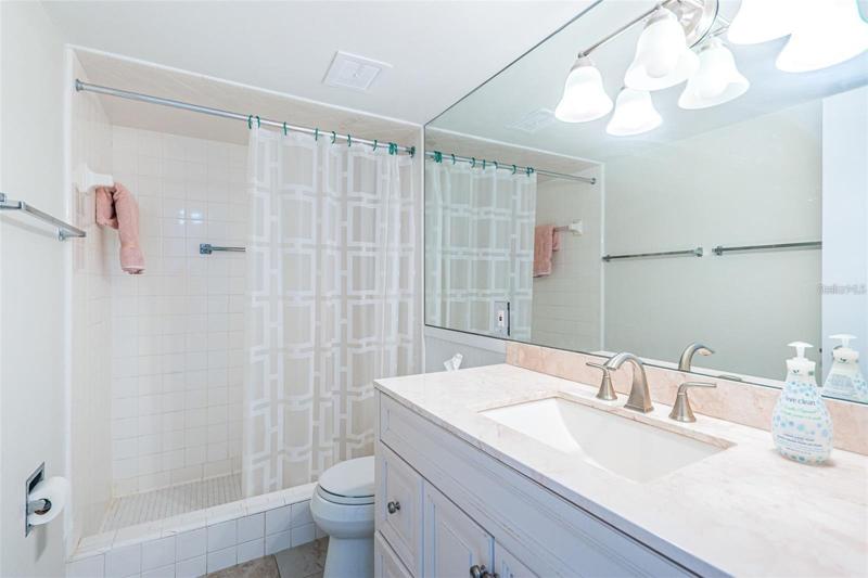Bright bathroom with mirror wall and tile shower.