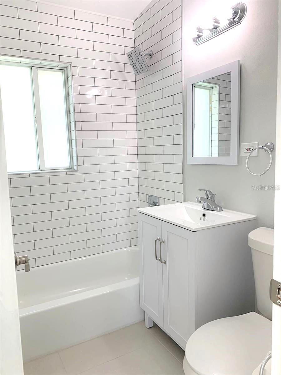 completely new bathroom features modern subway tile backsplash similar to the kitchen for a cohesive look