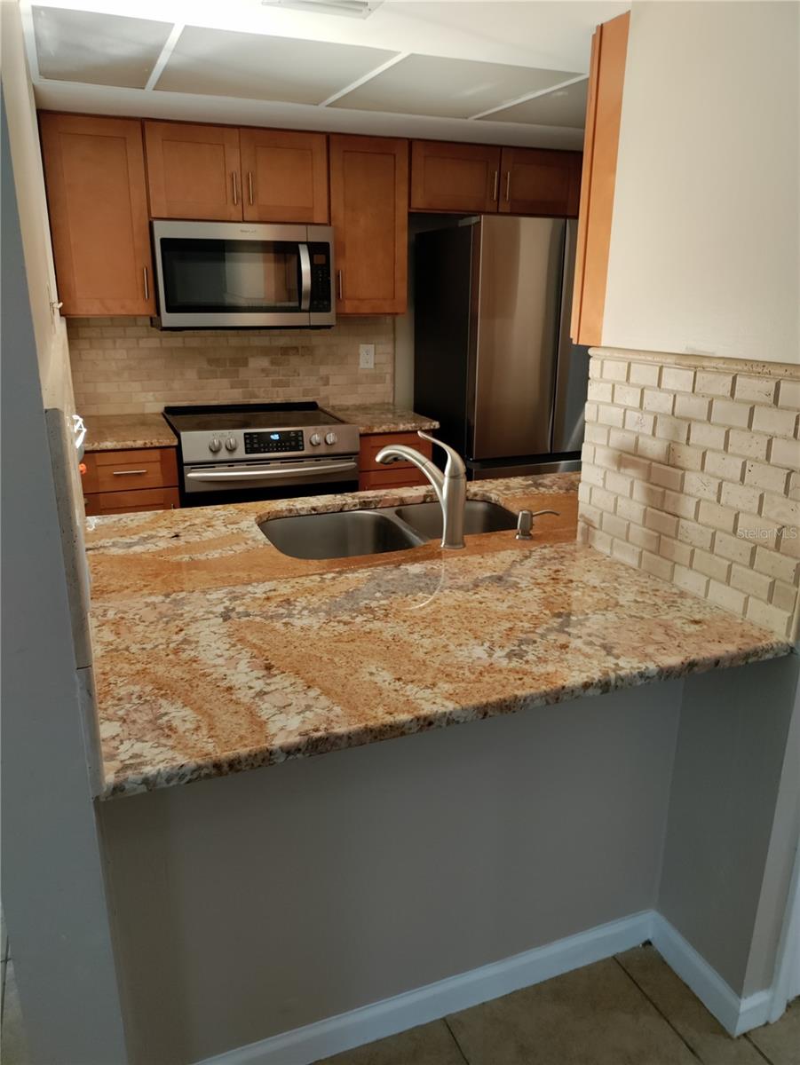 Open concept, mini island with stone counter top.