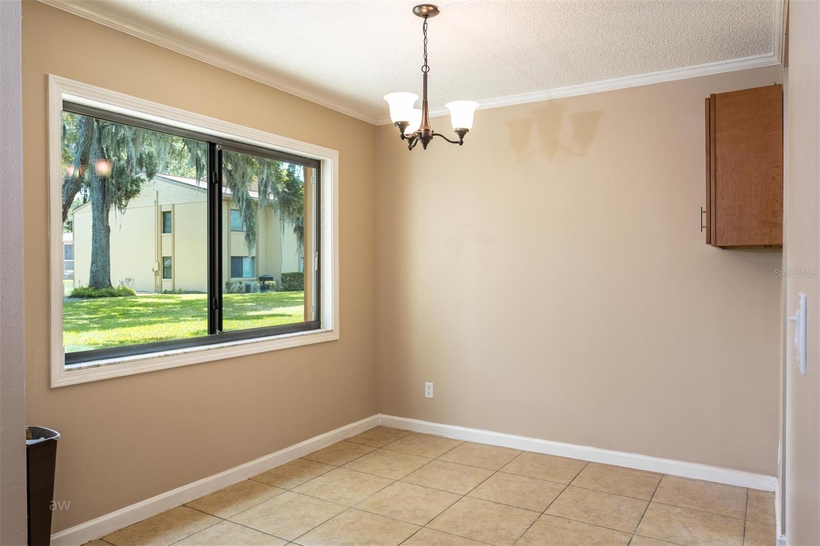 Dining area with natural light pouring in from large window facing pond &amp; fountain.