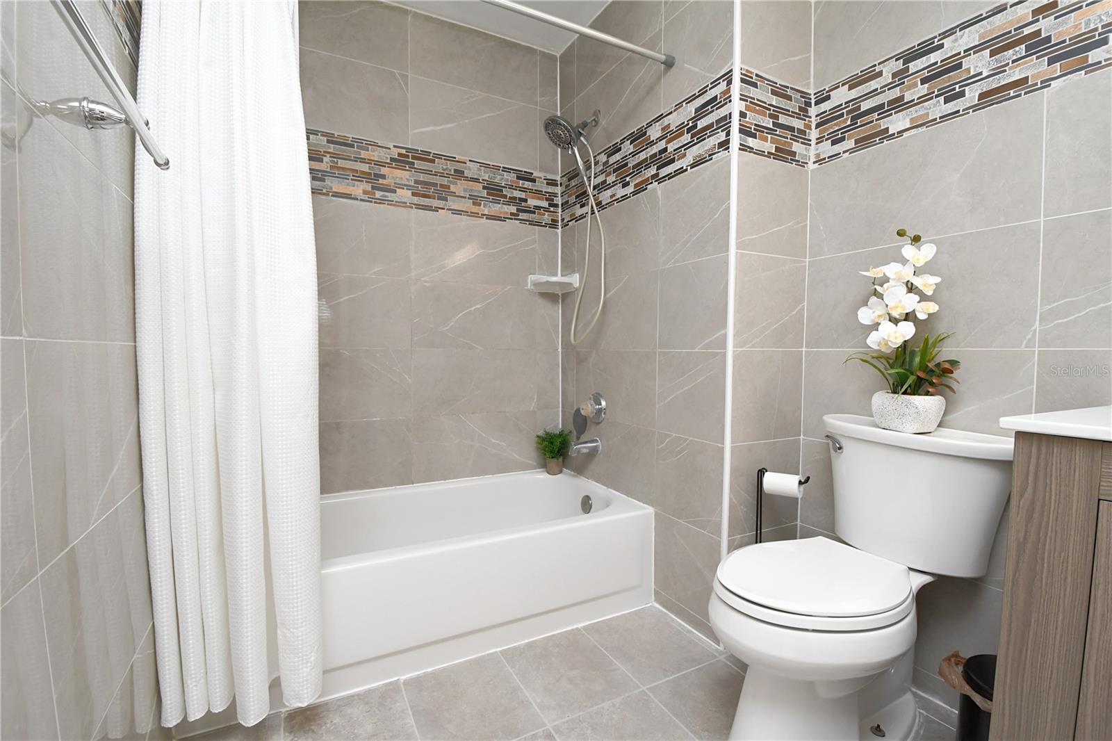 Master bathroom features a low/easy accessible bathtub, sleek tiles, double vanity with modern vessel sinks and contemporary lighting.