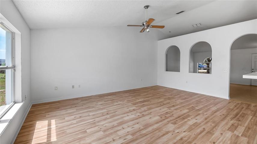 Great room with new flooring connected to kitchen & dinette. Arch ways to front rooms.