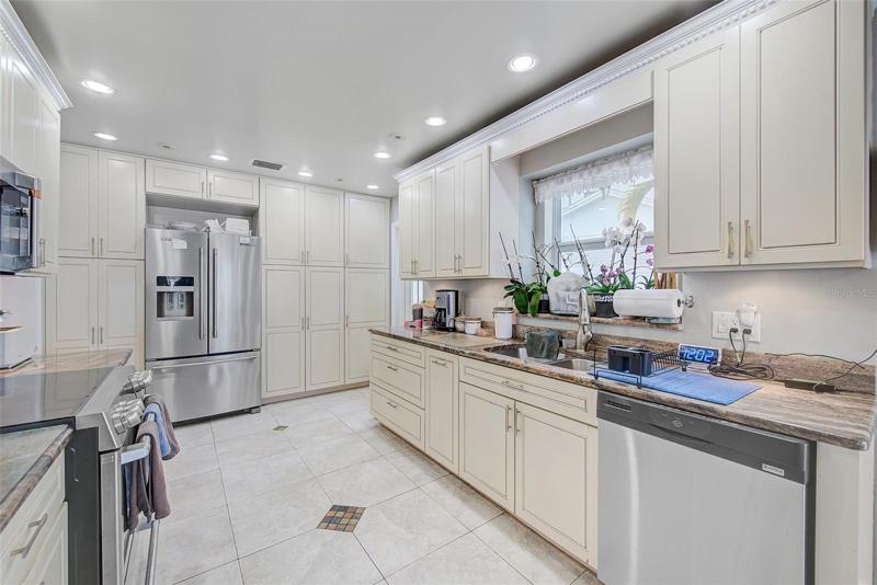 Chefs kitchen with tons of cabinets, counters, canned lighting and tile floors.