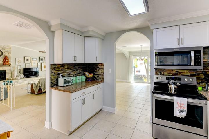 The kitchen has two arched entrances, one from the dining area and the other from the living room