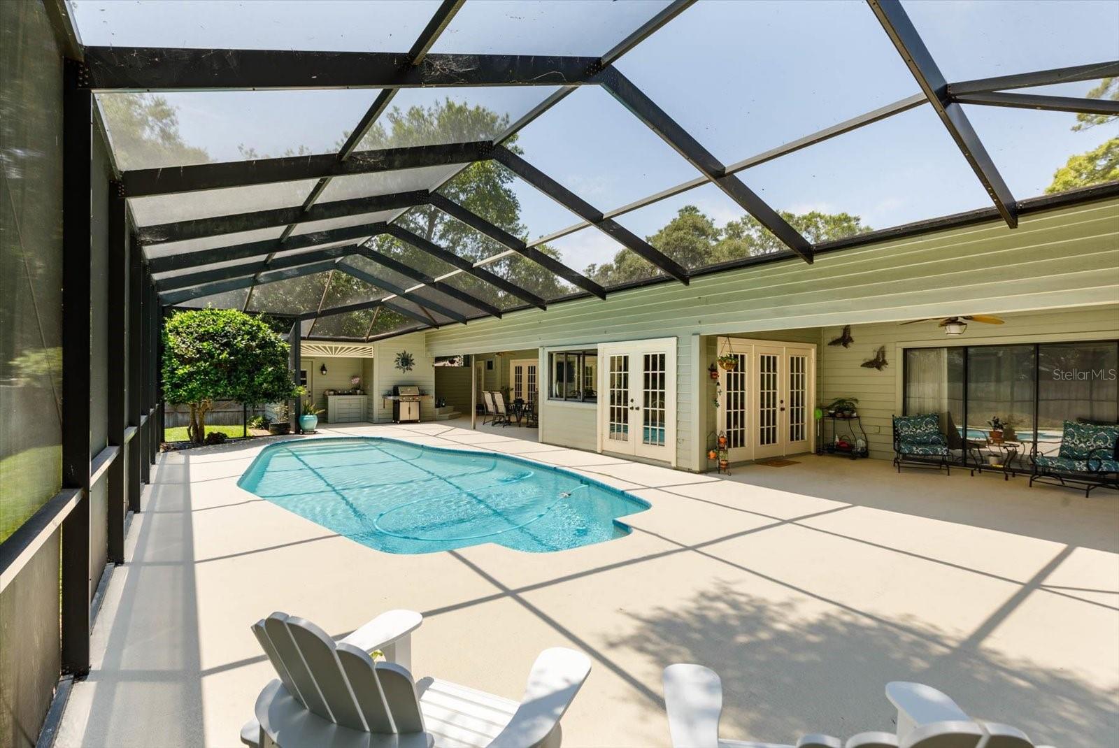 Pool deck with view to outdoor living area, cabana bath in the distance.