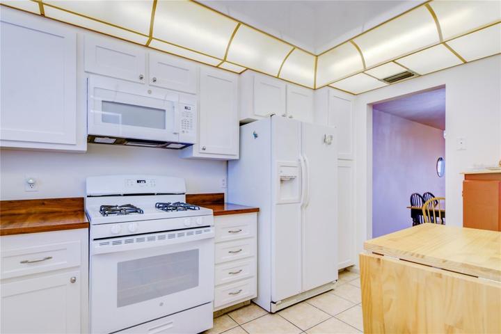 GAS cooking! Bright-white appliances compliment bright-white shaker cabinetry and butcher block countertop in the spacious kitchen.