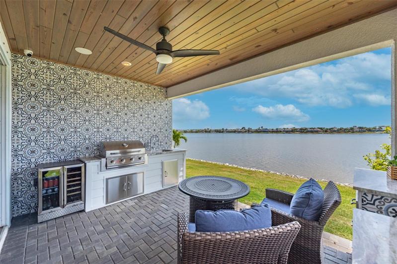 Outdoor kitchen with grille, refrigerator and sink.