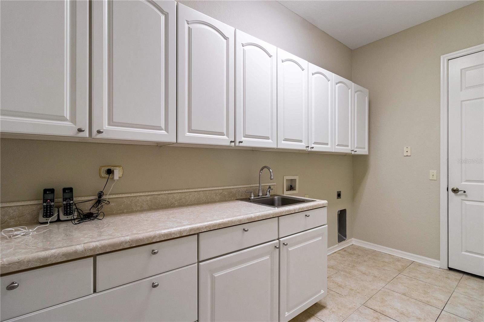 Spacious Laundry Room with plenty of storage. counter space for folding, sink for hand washing delicates, and door leading to garage