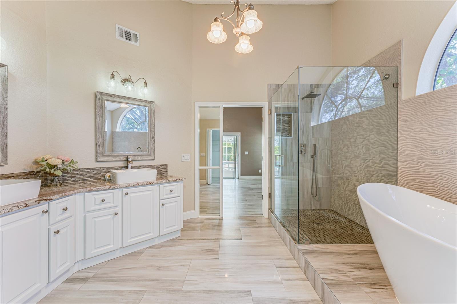 Primary en-suite bath features granite counters and custom tile shower