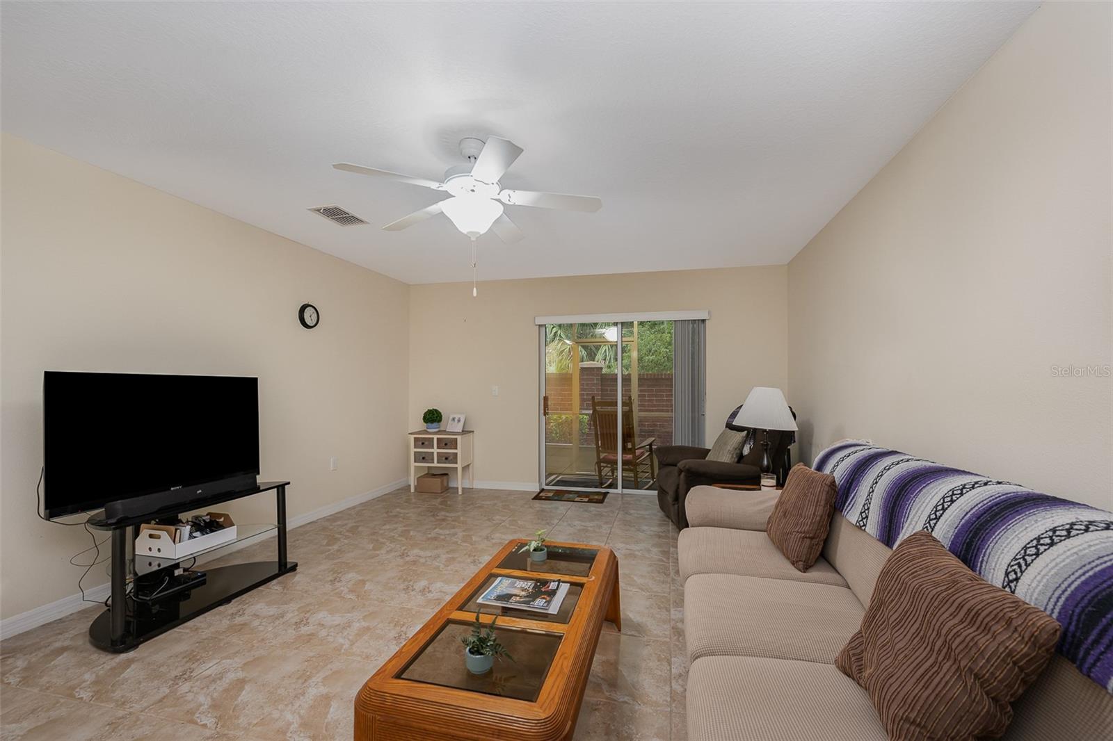 Spacious tiled living room overlooking screened-in back porch
