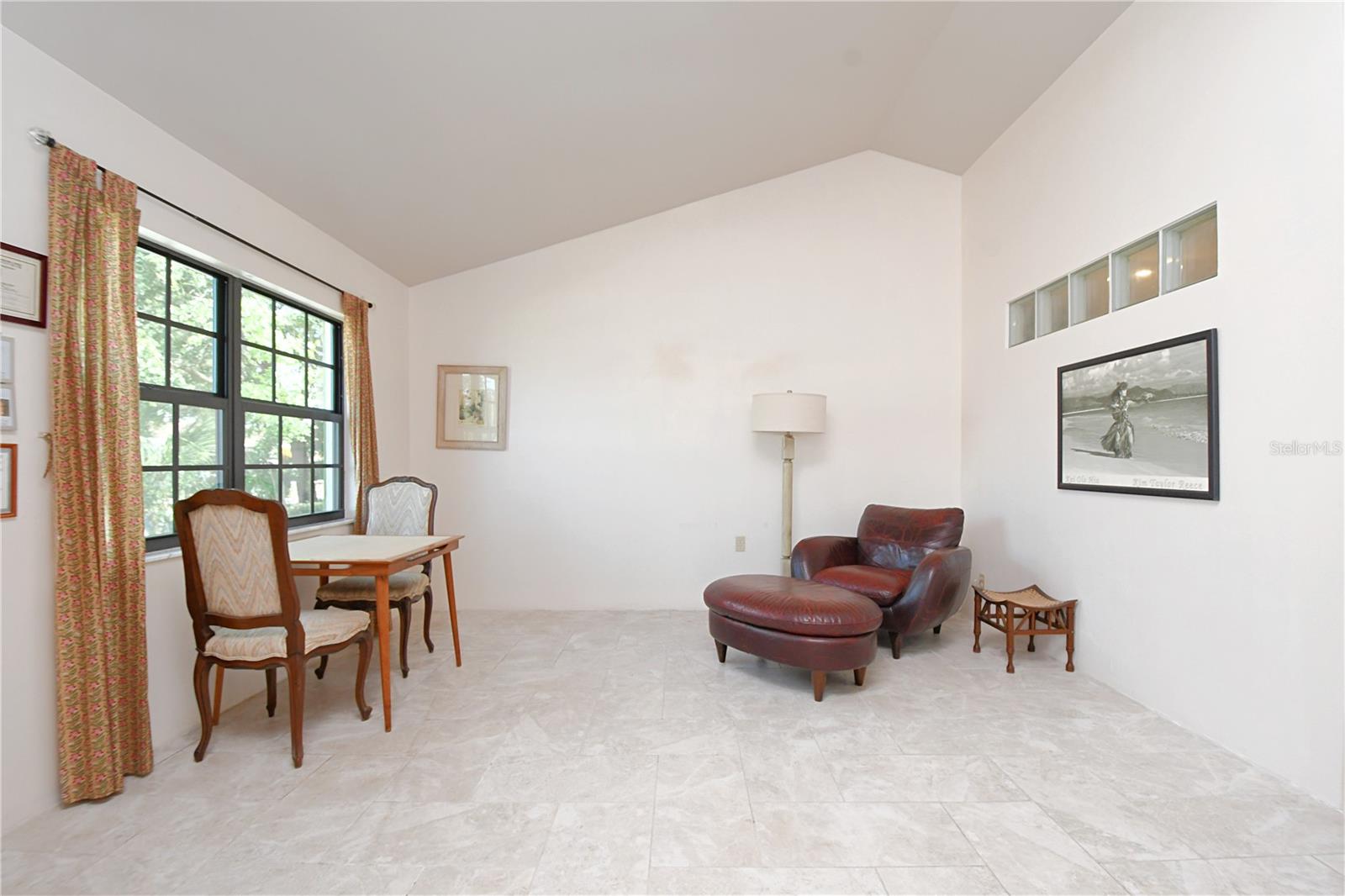 The front entry opens to a spacious living area with vaulted ceilings and a picturesque window that bathes the room in warm, natural light.