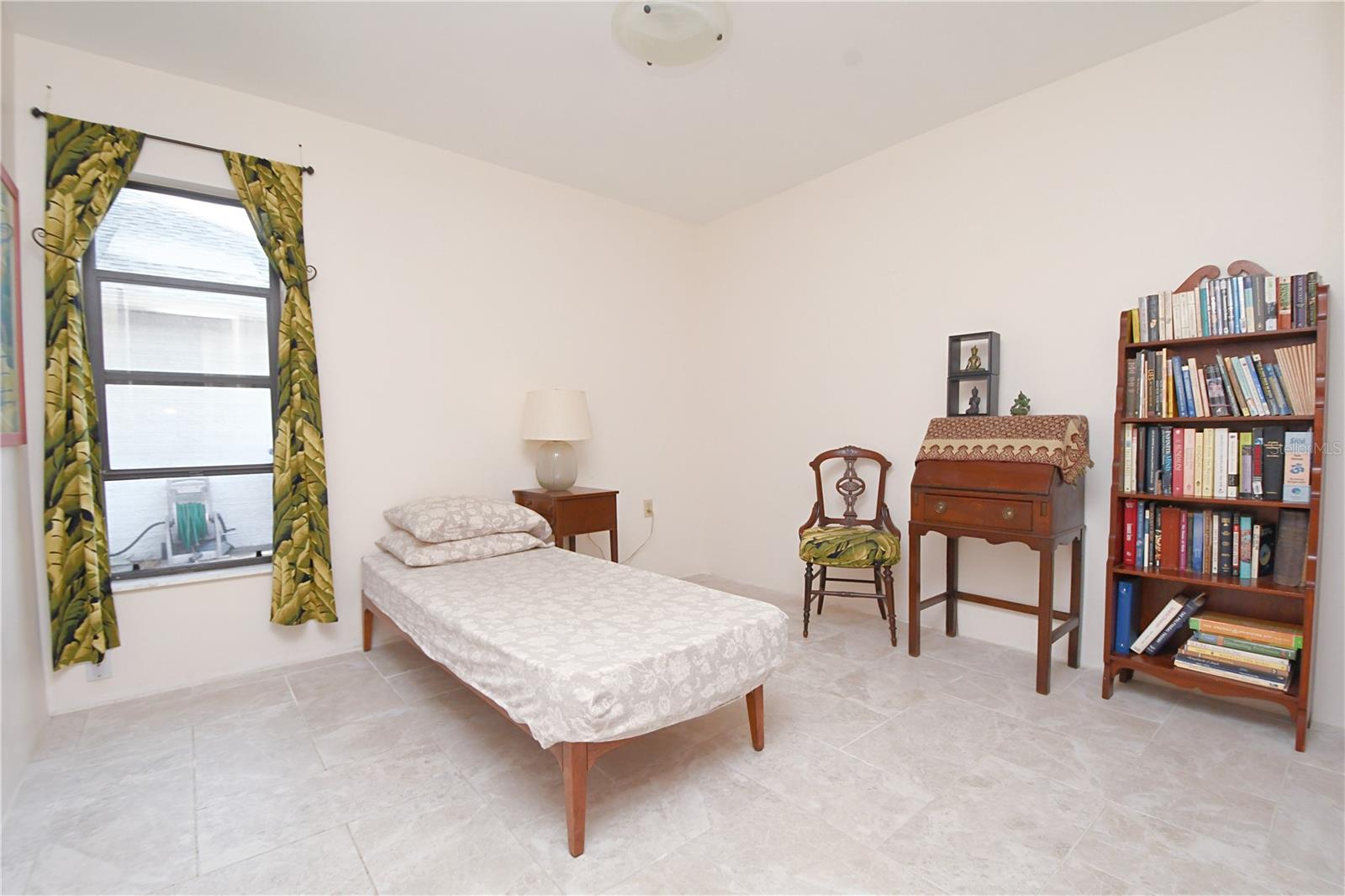 Bedroom two is light and bright, with neutral colors, a built in closet and ceramic tile flooring