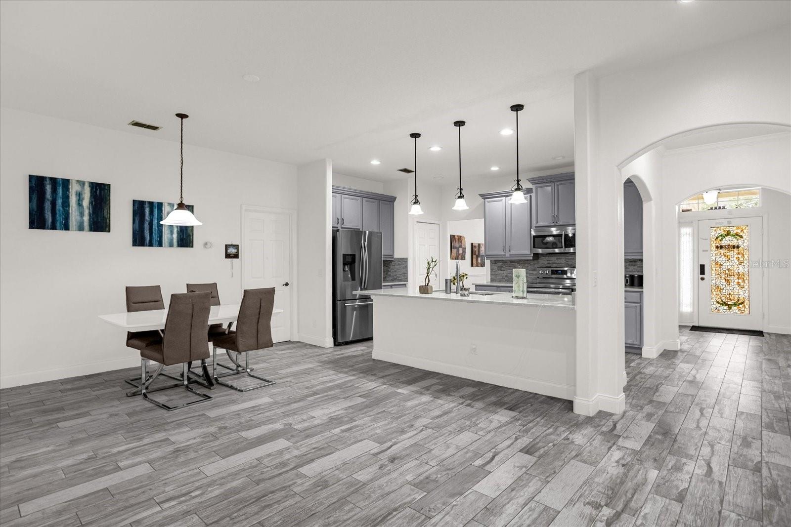 The Kitchen has Gray Cabinets, Quartz counters, stainless appliances and large Breakfast bar. This is a very open part of the home and also has spacious casual dining area. The door near the dining table leads to laundry and garage.