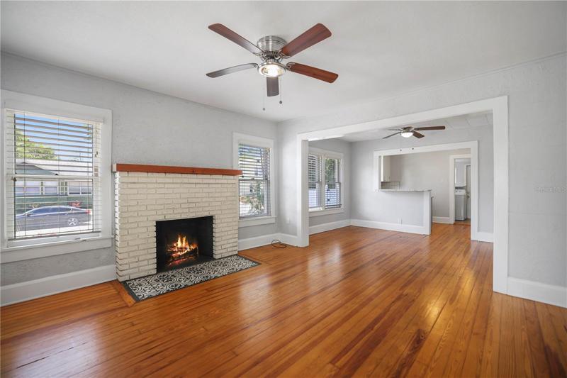 Brick fireplaced living room with hardwood floors. Open Floor Plan.